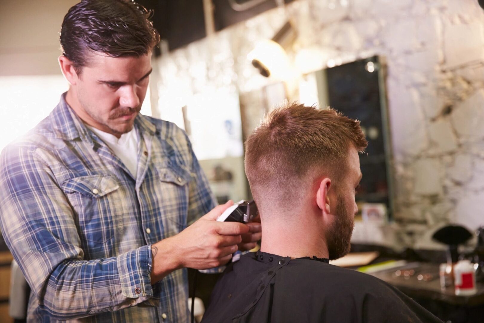 A man getting his hair cut by another man.
